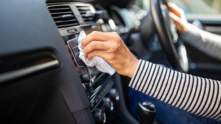 一位妇女用抹布擦拭汽车仪表板上的通风口