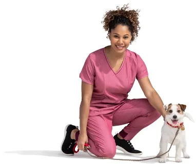 A kneeling woman in a pink outfit pets her terrier